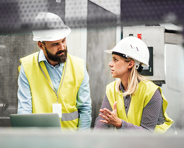 Two people in helmets in the warehouse