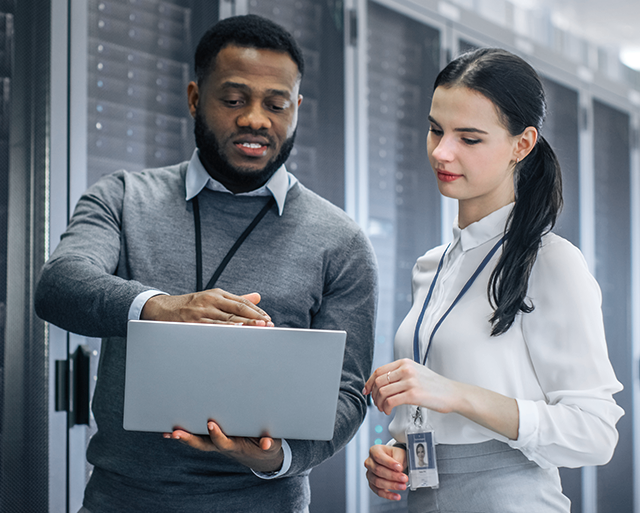 Two people with a laptop in the server room