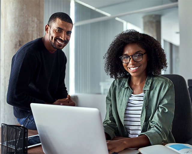 Two team members are sitting together with laptop and smiling