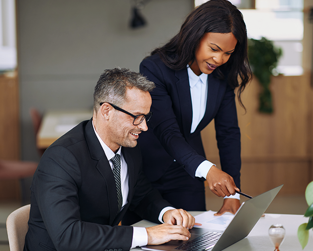 Woman and man are looking on a laptop screen at the office