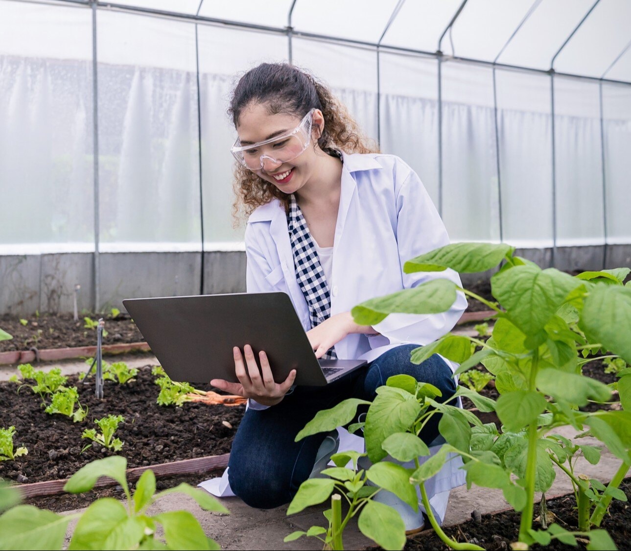 Greenhouse worker smiling on laptop